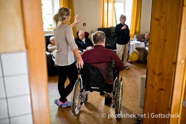 Bewohner im Aufentaltsraum mit einer Mitarbeiterin der Seniorenwohngemeinschaft, Marienrachdorf
