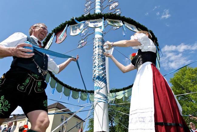 Bändertanz unter einem festlich geschmückten Maibaum.