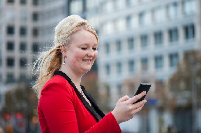 Eine junge Frau surft mit ihrem Handy im Internet.